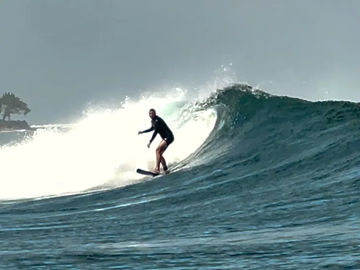 Surfer riding along the face of a breaking wave in a balanced surfing stance